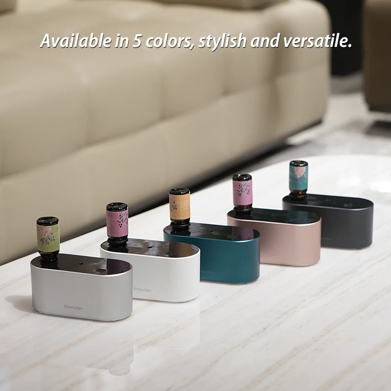 KINSCOTER waterless aroma diffusers in silver, white, green, rose gold, and black with essential oil bottles on marble surface.