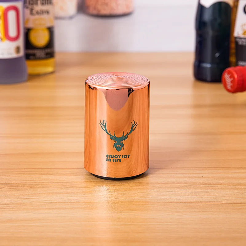 Single copper can opener with deer design on a wooden surface, with beverage bottles in the background.