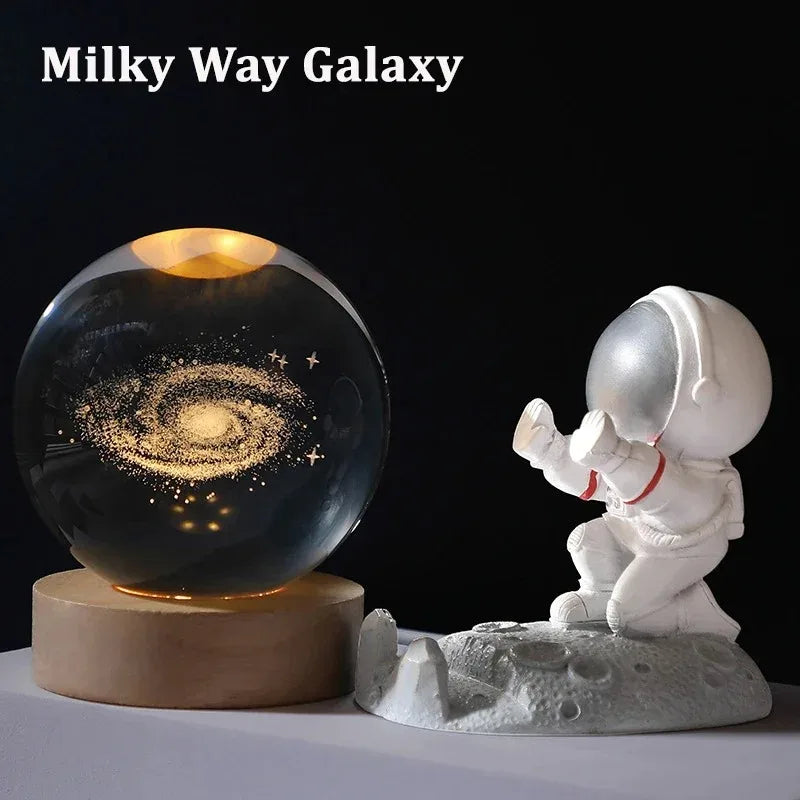 Glass ball displaying the Milky Way galaxy with an astronaut figurine on a dark background