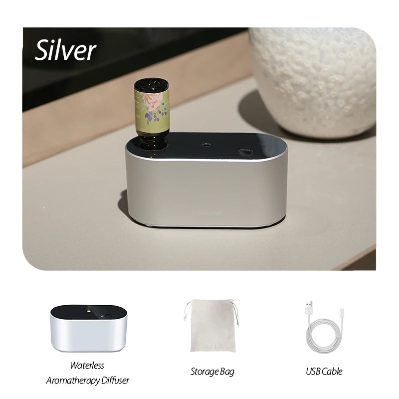 Silver KINSCOTER waterless aroma diffuser with essential oil bottle, storage bag, and USB cable on a minimalist surface.