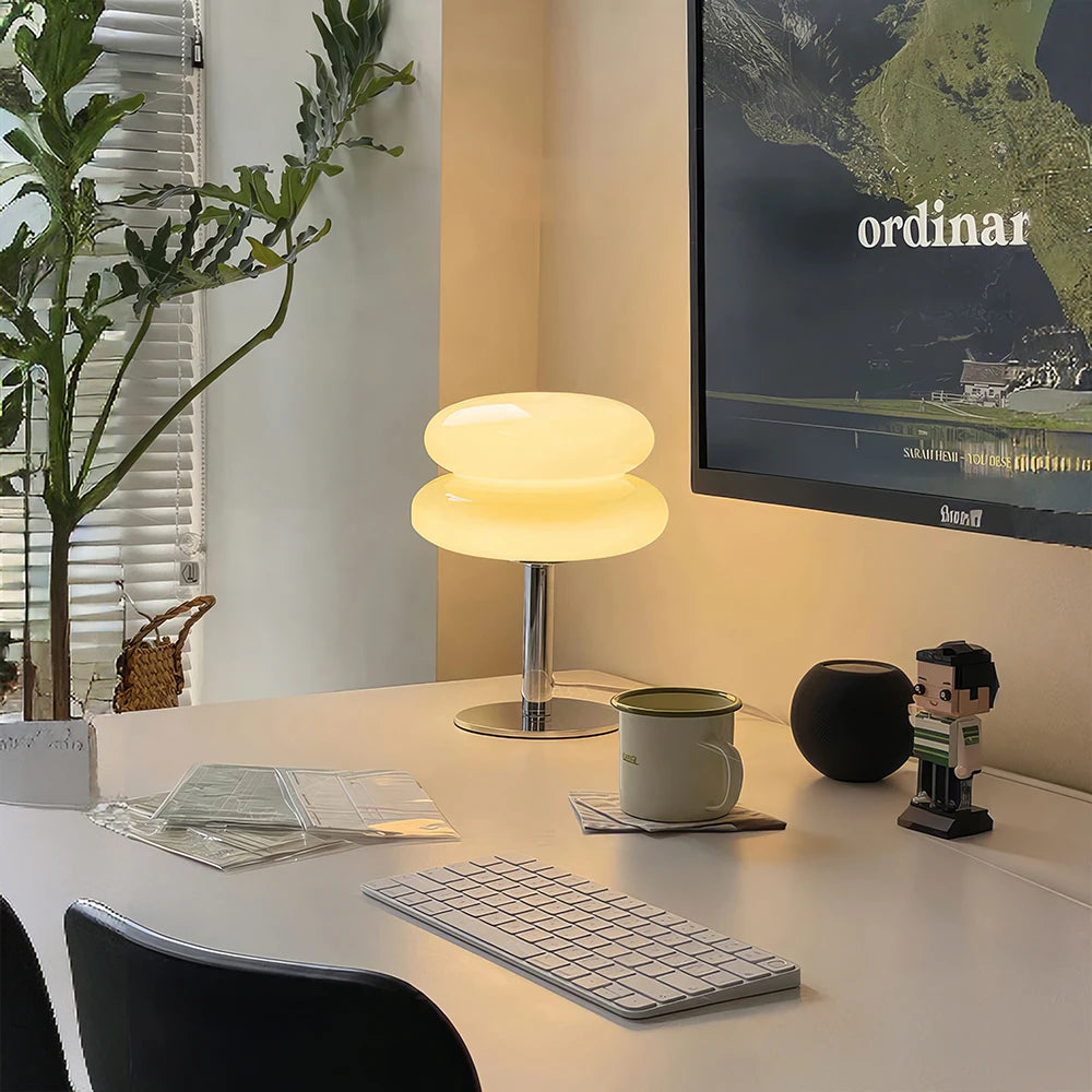 Modern office desk setup with a lamp, monitor, mug, and decorative items.
