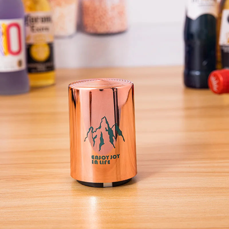 Single copper can opener with mountain design on a wooden surface, with beverage bottles in the background.