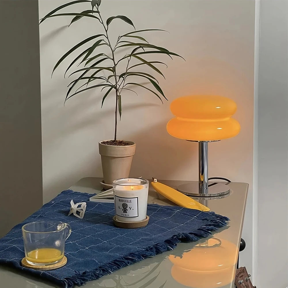 Table with candle, glass, banana, and lamp in a room setting