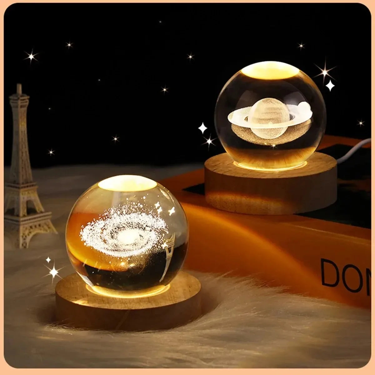 Two glass ball night lights with celestial designs on a surface with a blurred background.