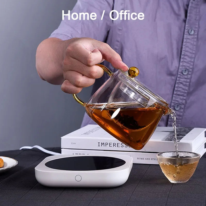 Pouring tea from glass teapot using smart mug warmer for home or office